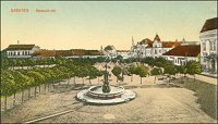 A Kossuth tér a Megyeháza ablakából - előtérben a kúttal. Szilágyi Dezső szinezett képeslapja (1914). Forrás: a Szentesi Levéltár képeslapgyűjteménye